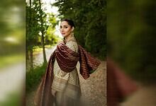 Elegant woman in traditional attire walking in lush green park during daytime.