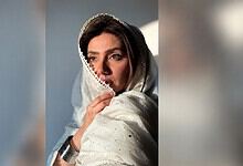 Mahira Khan wearing a white traditional dress with a headscarf, looking contemplative.
