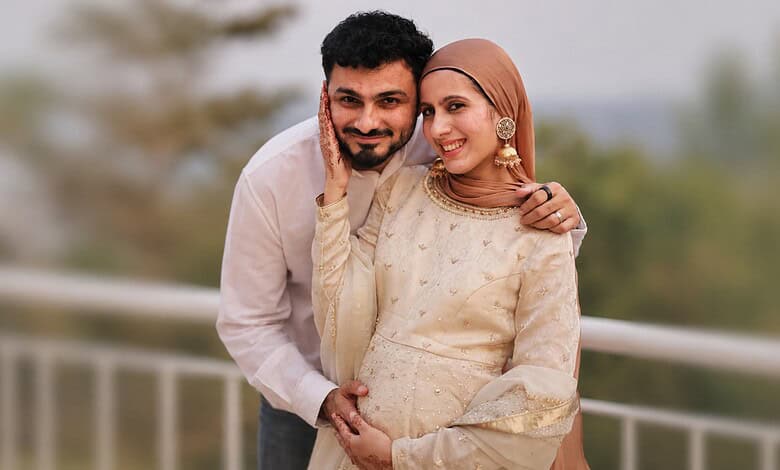Joyful couple with a newborn, celebrating their first child, outdoors with a blurred background.