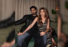 Nikki Tamboli sitting with a man in a cozy indoor setting, both looking at the camera.