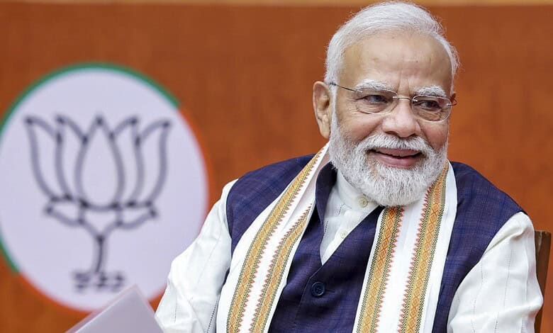 Prime Minister Narendra Modi smiling during Khelo India sports event with BJP logo in background.