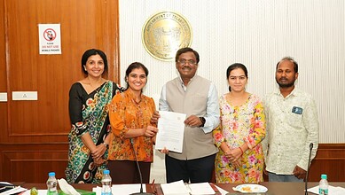 Group of five people at TOMCOM signing event, smiling and holding a document.
