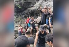 Group of people at Naneghat Reverse Waterfalls, some taking photos and exploring the rocky area.