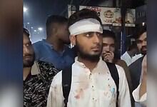 Madrassa student with a bandaged head surrounded by people in a crowded area.