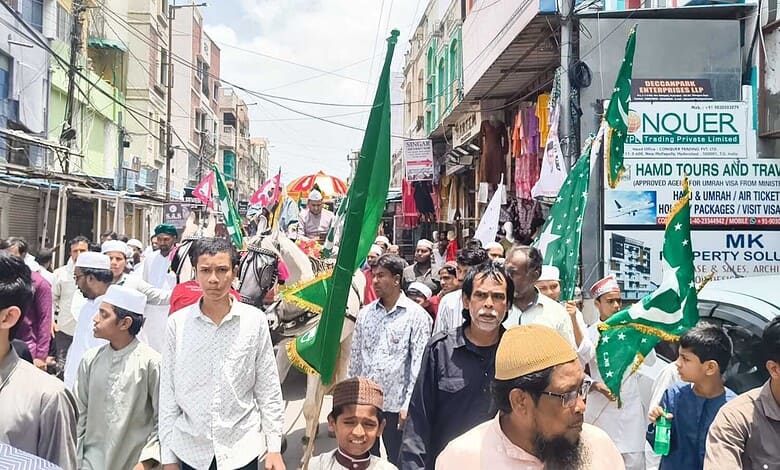 Crowd participating in Milad-un-Nabi procession in Hyderabad with flags and banners.