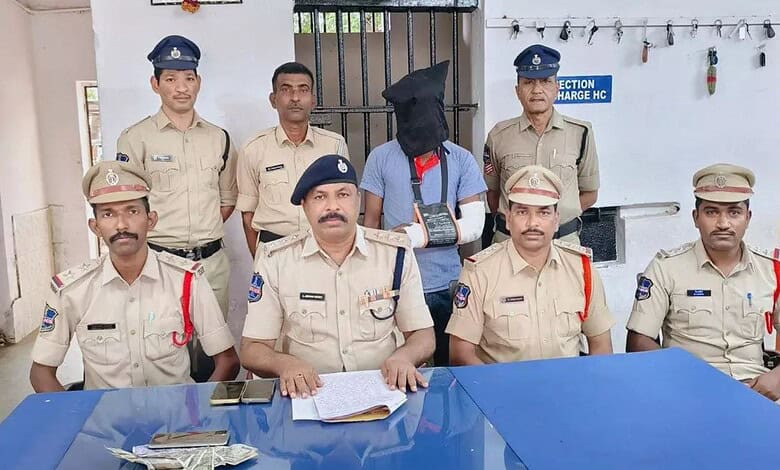 Police officers with a man in a hoodie and mask in a police station.