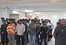 Crowd of police officers and civilians gathered in an indoor space during a public event.