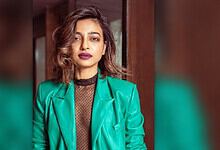 Radhika Apte in a teal blazer and black top, looking confidently at the camera.