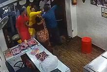 People involved in a physical altercation inside a small shop or restaurant.