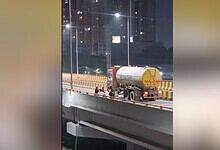 Women dancing on Bachupally flyover at night, with city lights in the background.