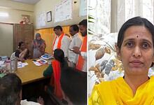 Women and men in a meeting room, some wearing orange scarves, discussing documents.