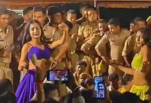 Women dancing in front of police officers during a public event in India.