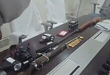 Collection of firearms, ammunition, and related equipment on a conference table.