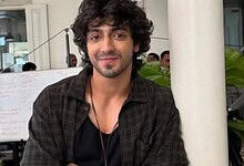 Ahaan Panday with curly hair and a beard, smiling in a casual setting.