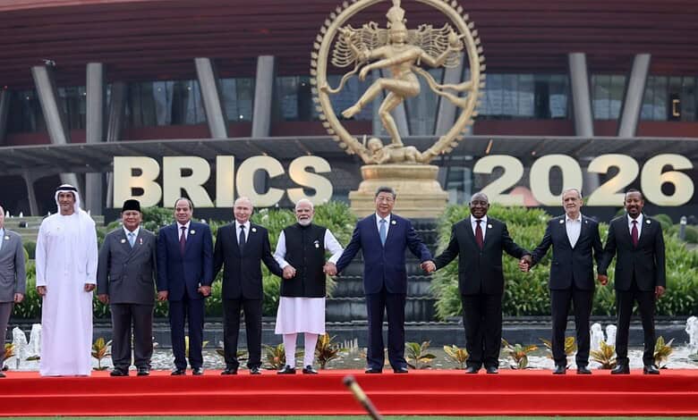 BRICS leaders standing together at the 2026 summit in front of a large Ganesha statue and BRICS 2026 sign.