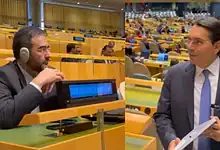 Israeli envoy and Iranian diplomat at UN meeting, engaging in discussion.