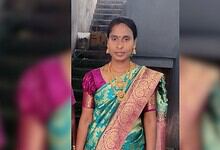 Indian woman wearing a colourful saree with gold jewellery, standing outdoors.