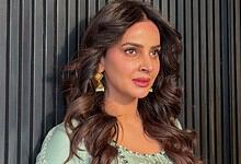 Saba Qamar with wavy hair and traditional earrings, looking to the side.