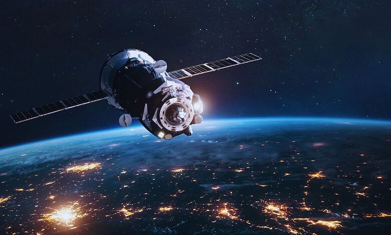 Satellite orbiting Earth with city lights visible on the surface at night.