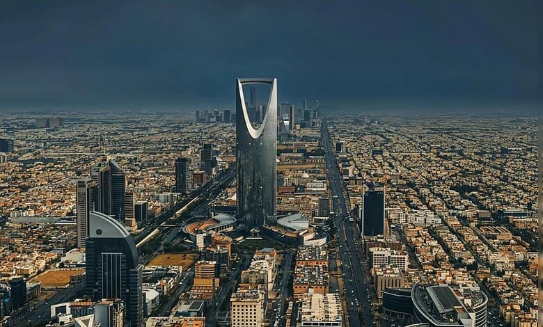 Aerial view of Riyadh city with Kingdom Tower under dark stormy sky.