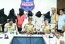 Seven suspects with covered faces and police officers during a press conference in Telangana.