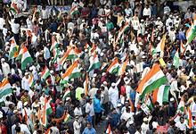Crowd of protesters holding Indian flags at a rally in India.