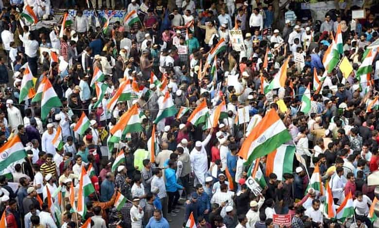 Crowd of protesters holding Indian flags at a rally in India.