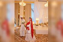 Bride and groom at wedding reception in elegant traditional attire, decorated venue.
