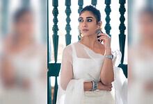 Nayanthara wearing a white saree with jewelry, posing thoughtfully indoors.