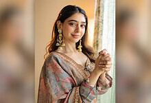 Niti Taylor wearing traditional Indian dress with jewelry, smiling softly indoors.