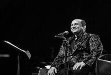 Rahat Fateh Ali Khan smiling while singing into a microphone during a live performance.
