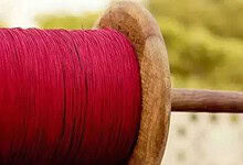 Close-up of a wooden spool with red thread, used for kite flying.