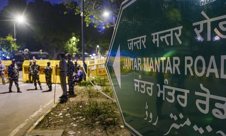 Jantar Mantar Road sign in Delhi with police officers and vehicles in the background.