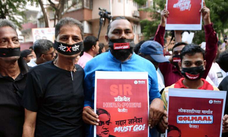 Protesters with masks hold signs during Nagpur anti-CEC protest, demanding justice.