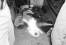 Crime scene with a blurred body on the floor in a room, surrounded by two people.
