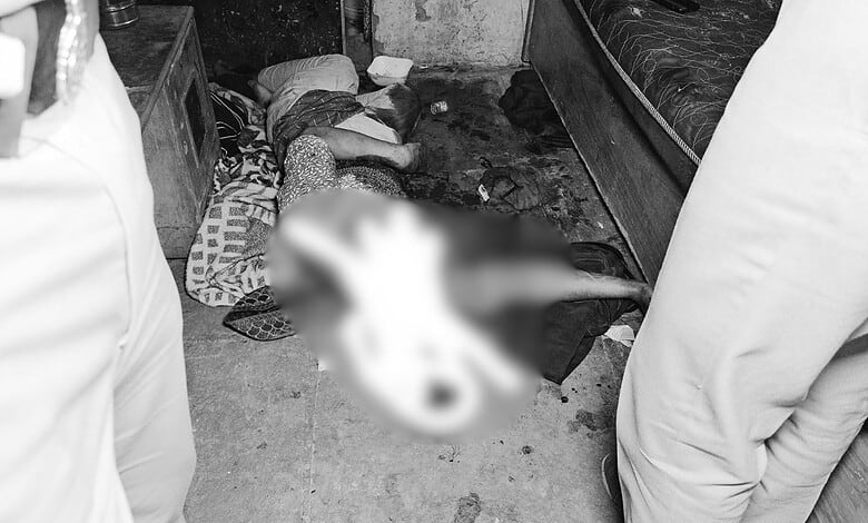 Crime scene with a blurred body on the floor in a room, surrounded by two people.
