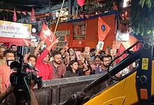 Crowd of protesters with flags and banners during a political rally at night.