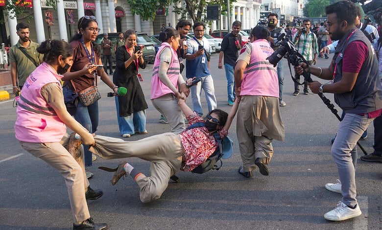 Women journalists protesting, some being detained by police on the street.