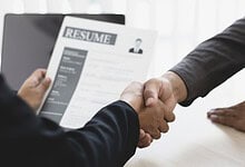 Handshake between a job seeker and interviewer during a resume interview at a professional setting.