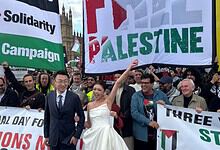 Newlywed couple poses with demonstrators holding Palestine banners in London.