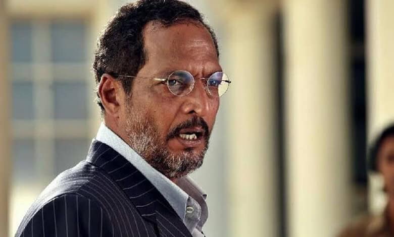 Nana Patekar in a scene from a film or event, wearing glasses and a pinstripe suit.