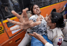 Policewoman detains woman during protests in Delhi, tense confrontation at the scene.