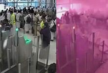 Crowd of pilgrims and airport staff during strike at Riyadh airport with pink smoke in background.