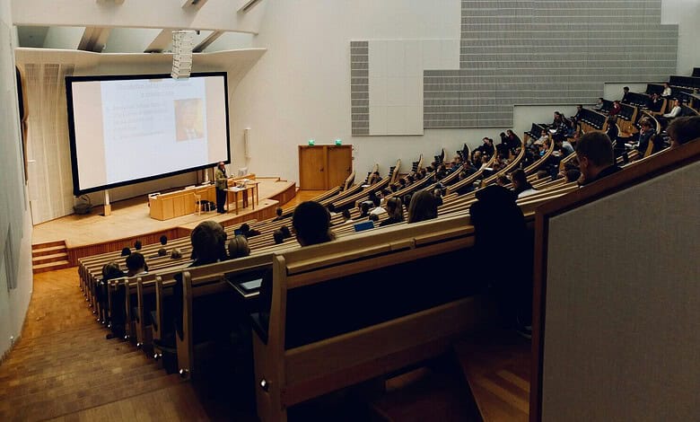 Audience attending a training session in a spacious, modern auditorium with a presenter at the front.